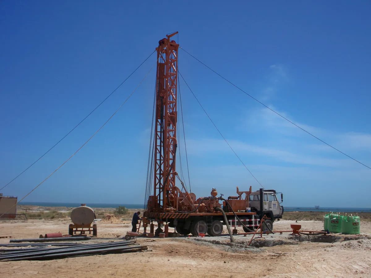Truck-mounted water well drilling rig working at a remote field site
